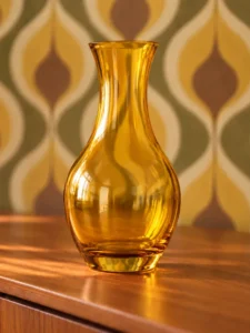 An amber-colored glass vase in a room with 1970s decor