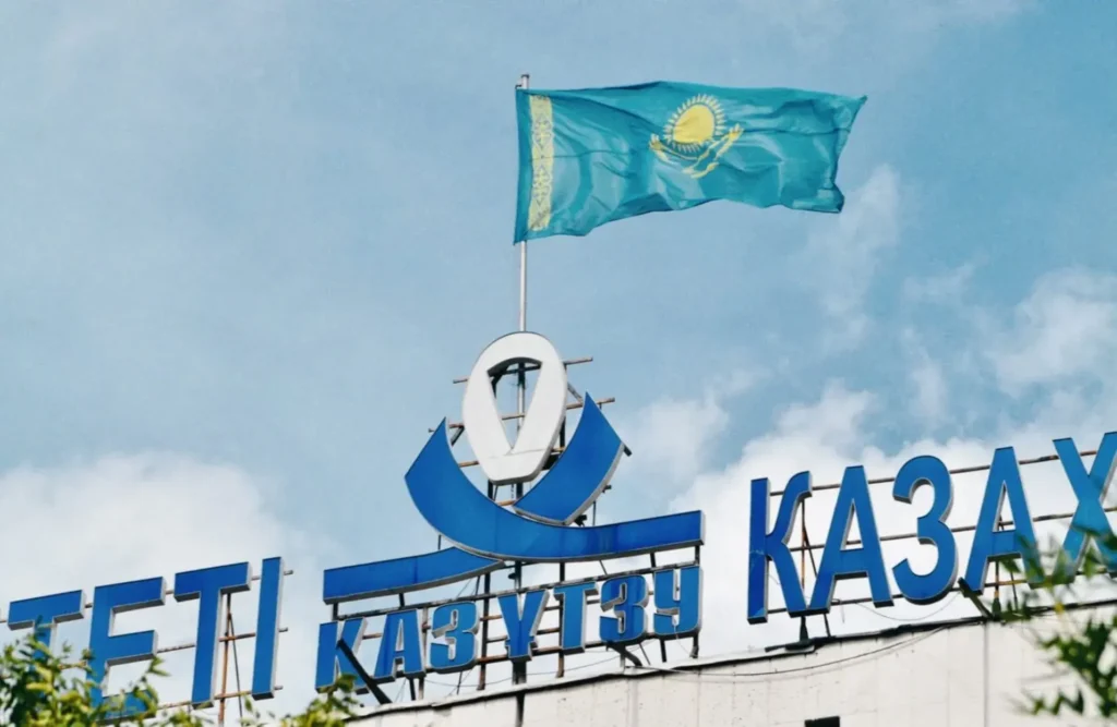 The flag of Kazakhstan flying over a building in Almaty