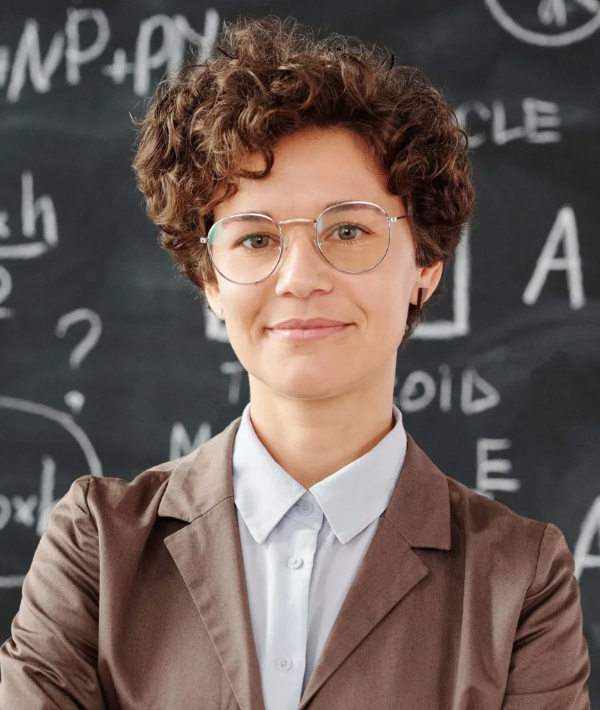 An example of an academic headshot showing a dark-haired woman with glasses in front of a chalkboard