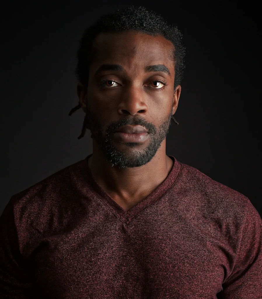 An example of an actor headshot showing a dark-haired man with a dramatic expression in dramatic lighting